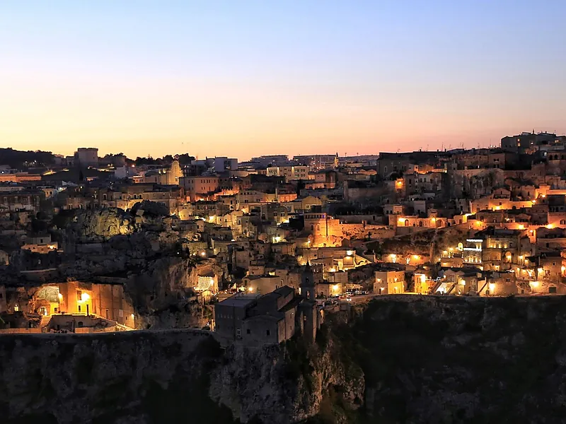 Matera al crepuscolo, con le case di pietra illuminate.